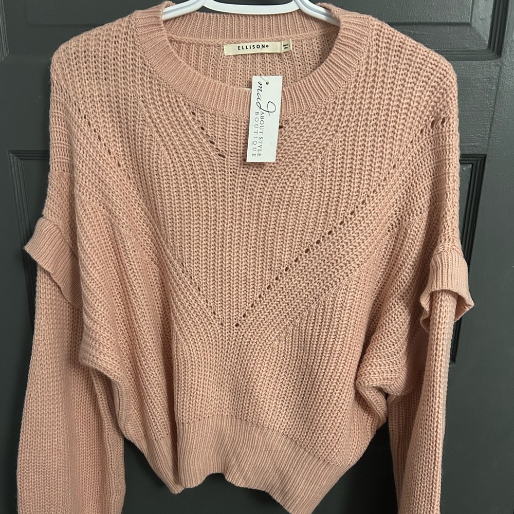 Pink sweater with details on shoulders, slightly cropped length